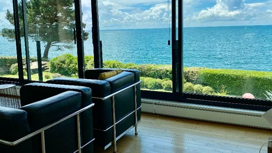 Salon vitré avec vue mer depuis une maison en bord de mer en Bretagne